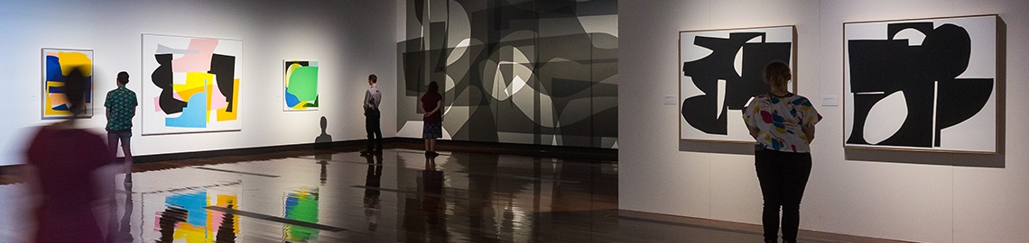 People standing in Caboolture Art Gallery, viewing different abstract artworks